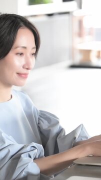 オシャレな明るいオフィスでノートパソコンで仕事をする日本人女性 オフィスワーク・ビジネスシーン縦動画の横顔