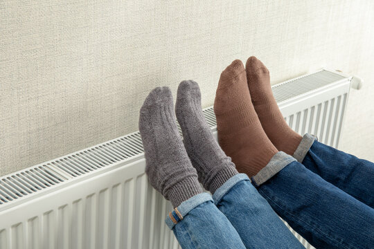 Heating season. Feet in wool socks enjoy warmth from radiator during heating season. Comfort concept