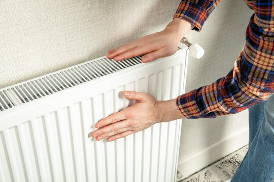 Heating season. Person checks warmth of radiator in cozy home environment. Heating season concept