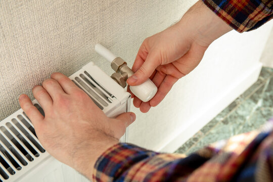 Heating season. Man operates radiator valve, ensuring warmth in home during heating season