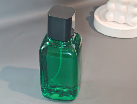 Elegant green glass perfume bottle with transparent fragrance on a clean minimal background and generous copy space. Suitable for fragrance branding, luxury perfume advertising, cosmetic packaging