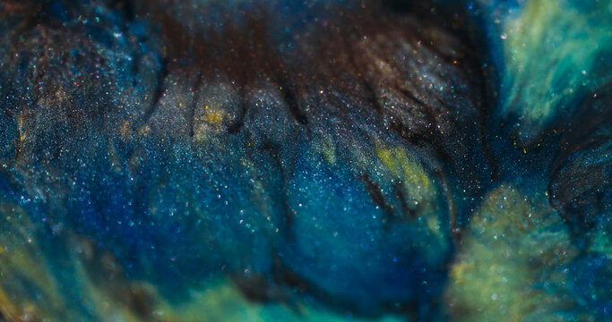 Acrylic sparkling bokeh. Paint stream. Blue green liquid pigment wave spill on black gray glitter flare mixing color abstract background.