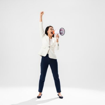 A confident businesswoman in a white blazer and navy trousers stands dynamically against a clean white studio background, passionately shouting into a megaphone with her right arm raised high