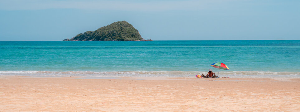 Tropical beach landscape with colorful umbrella and island background in sunny day.Thailand travel summer concept.