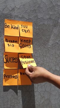 Hand Peeling Off Motivational Sticky Notes