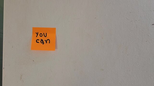 Person Sticking Note with Encouraging Phrase You Can