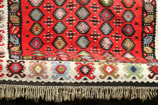 Traditional red Balkan woven kilim rug with geometric ornaments, intricate border, and fringe detail