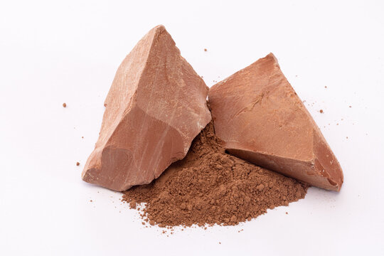 Close-up of Two Reddish Brown Clay Chunks with Fine Clay Powder Piled Between on White Background