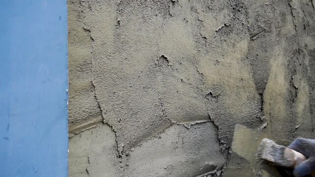 Mason plastering concrete wall with cement mortar using trowel