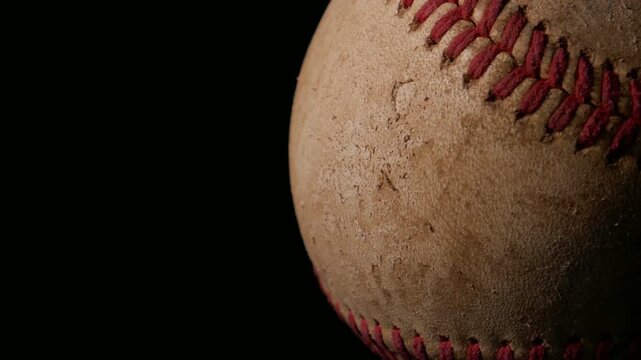 A closeup of a well worn baseball rotating isolated against a black background. Sports or game ball concept with copy space.
