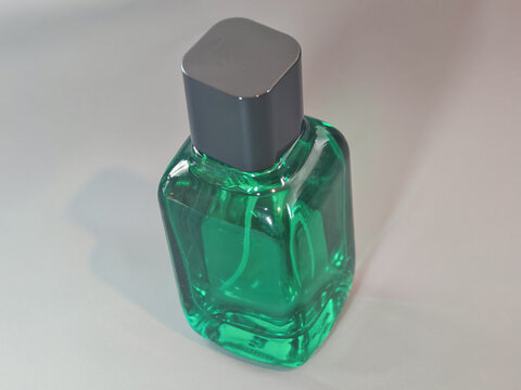 Clean commercial studio shot of square green glass cologne spray bottle featuring a matte dark cap. Targeted for luxury beauty branding, skincare packaging mockups, and minimal spa cosmetics marketing