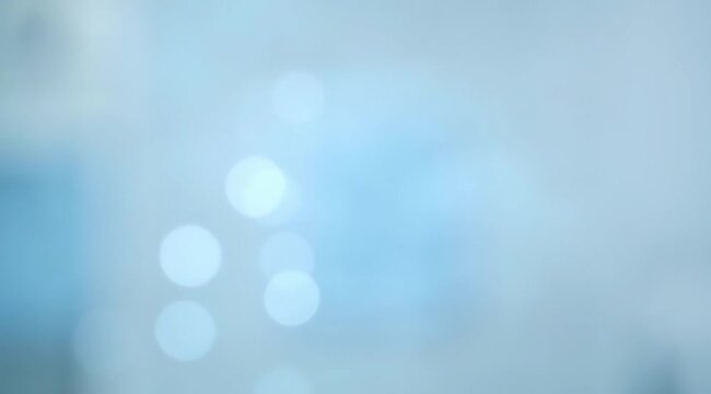 Abstract soft blue background with ethereal light bokeh circles, festive sparkling texture, dreamy atmosphere, elegant blurred overlay for cinematic video