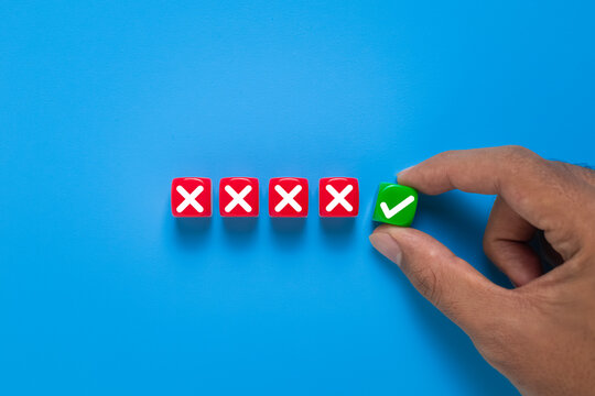 male hand put cubes with cross and check sign symbol. isolated on blue background. decision making concept