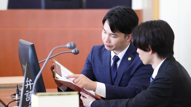 法廷で打ち合わせを行う若手弁護士と先輩弁護士
