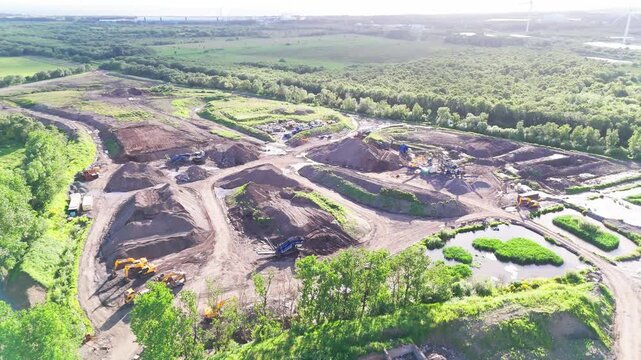 Active quarry and aggregate operations site on the west coast of Scotland, showing earthworks, heavy machinery and material stockpiles, aerial view