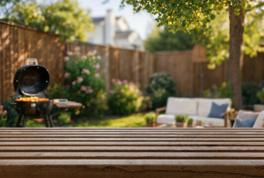 summer time in backyard garden with grill BBQ, wooden table, blurred background Stock Photo