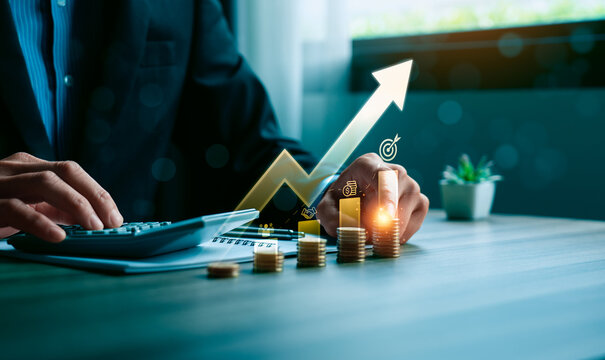 Business financial growth concept with professional using calculator beside rising coin stacks and digital arrow chart showing revenue increase investment strategy and profit success