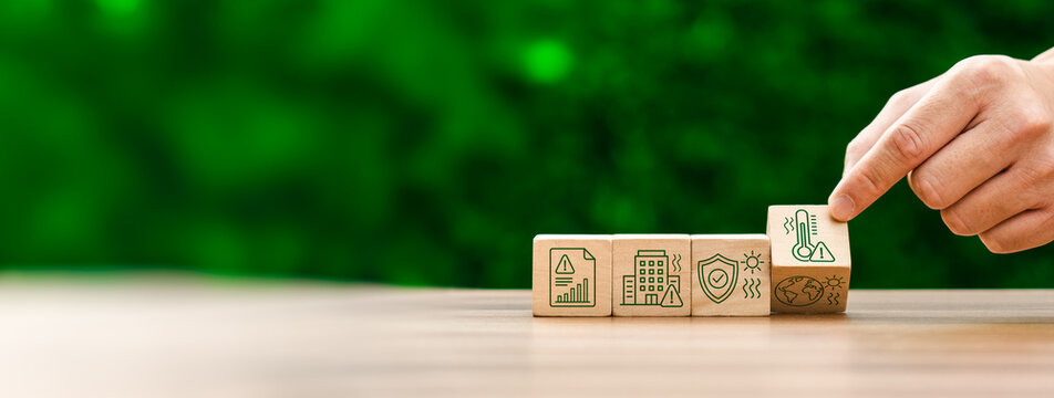 Climate risk management concept with hand placing heat warning icon cube on wooden blocks showing global warming impact urban safety environmental protection and sustainability planning