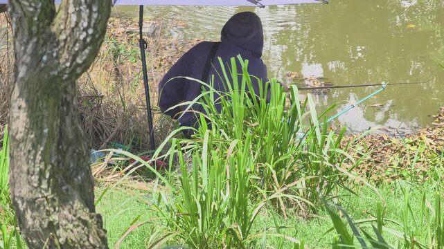 Weekend leisure : young local man fishing on a peaceful rural riverbank in the Mekong Delta, Vietnam