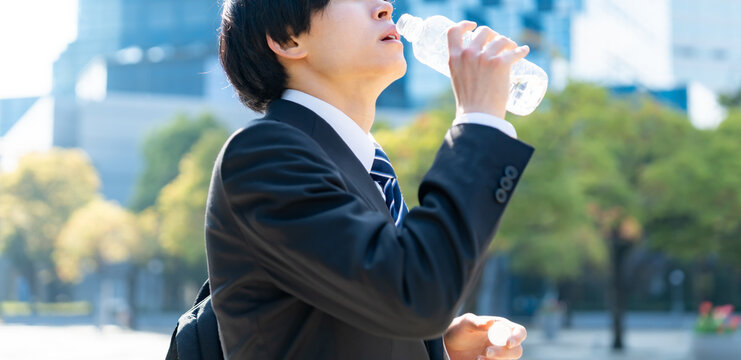 水を飲むスーツを着た男性