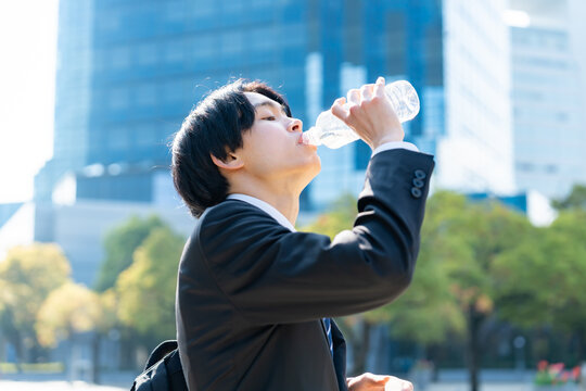 水を飲むスーツを着た男性