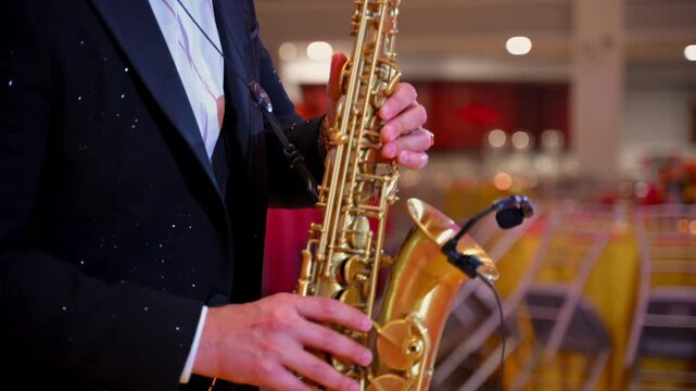 Close up of a professional saxophone player performing live during an elegant wedding reception or formal event. Musician in a tuxedo playing golden saxophone, creating a sophisticated atmosphere with