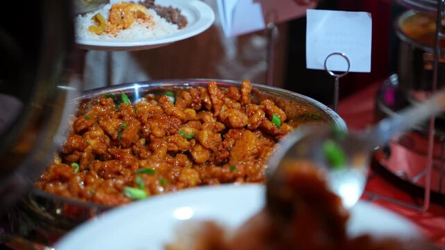 Close up of hands filling plates at a food station during a banquet, corporate event, or private celebration.