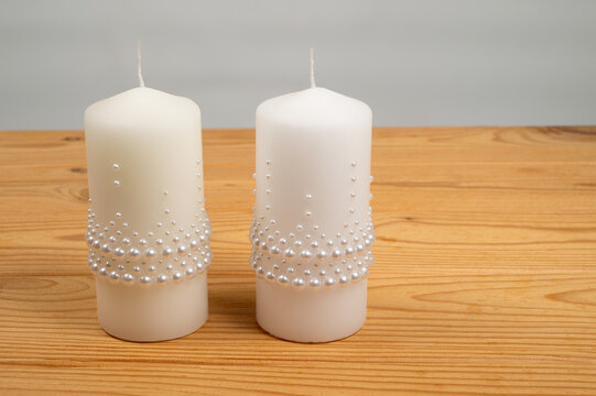 White decorative candles standing on a wooden surface.