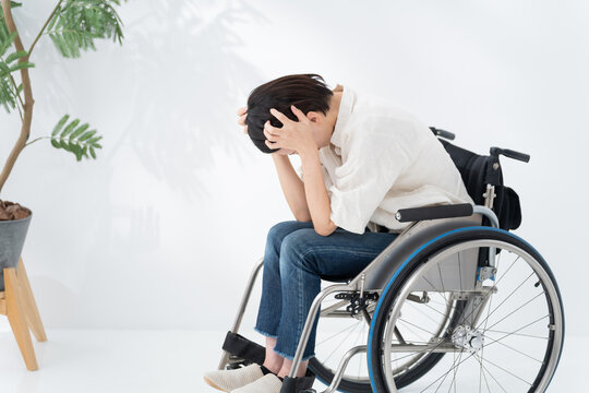 車椅子に乗る落ち込む女性
