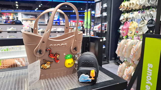 Crocs rubber tote bag and mini backpack pouch decorated with cartoon charms displayed on store shelf on July 21, 2026 in Bangkok, Thailand