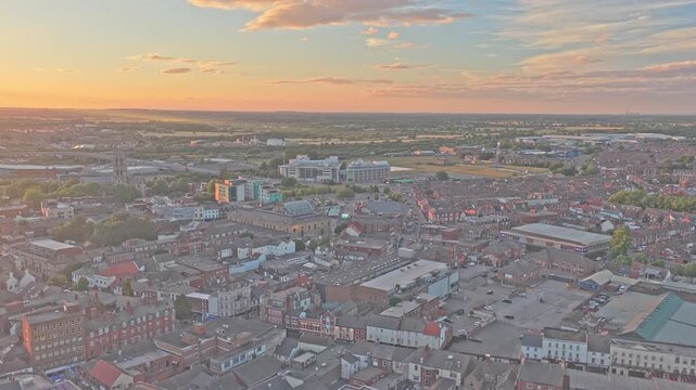 Doncaster town centre spreads across South Yorkshire, England, United Kingdom, with dense urban streets and the Civic and Cultural Quarter under warm sunset light, drone ascent.