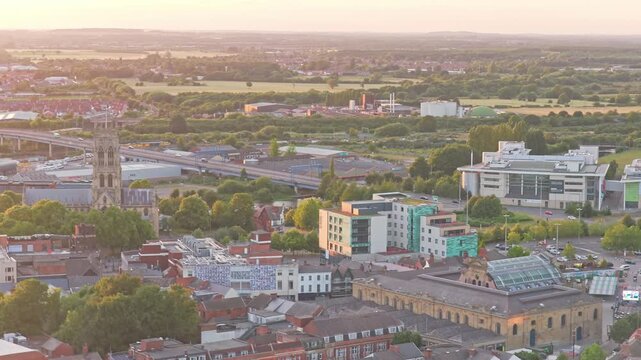 Doncaster Minster rises beside A19 St George's Way and Doncaster College at The Hub, Chappell Drive, Doncaster, South Yorkshire, England, United Kingdom, drone ascent.