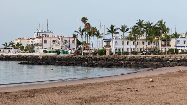 Morning light highlights the sandy beach and waterfront architecture of PuertodeMogan, showcasing the picturesque fishing village charm of GranCanaria