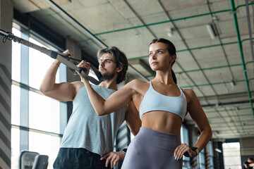 Fototapeta premium Young couple on body training with trx in gym.