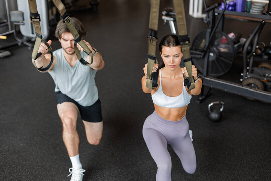 Young couple on body training with trx in gym.