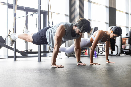 Young couple on body training with trx in gym.