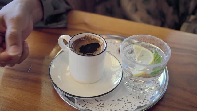 a young woman enjoys turkish coffee and water at a cafe table