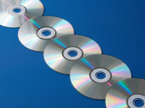 Row of Reflective Compact Discs Arranged Diagonally on Blue Background