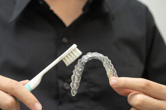 Man clean teeth brace removable retainer with brush.
