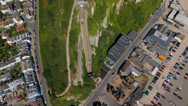 Static top-down aerial view of the East Hill Cliff Railway funicular in Hastings Old Town, capturing both carriages passing between the lower and upper terminals on the chalk cliffside.