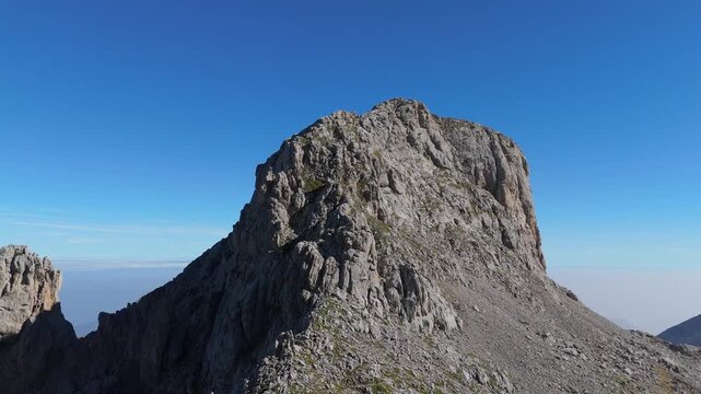 An aerial view of the majestic Picu Valdomingueru mountain in Asturias, Spain. The drone pans right, revealing rugged rock formations and breathtaking natural beauty in the Picos de Europa.