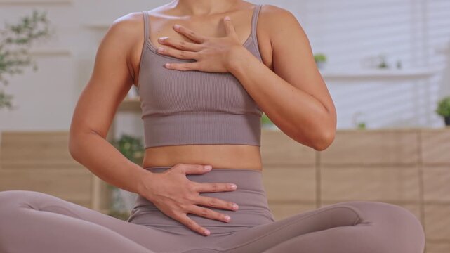 Woman yoga meditation hand chest abdomen home exercise breathing wellness practice seated posture indoor fitness health symptom