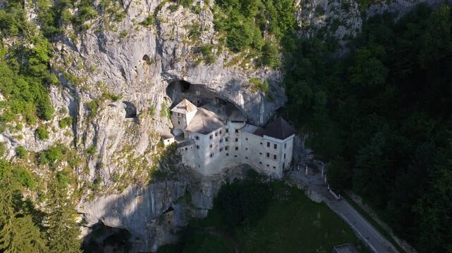 Predjama Castle built into a limestone cliff in the Inner Carniola region of Slovenia, showing the medieval fortress and surrounding rocky landscape - drone shot