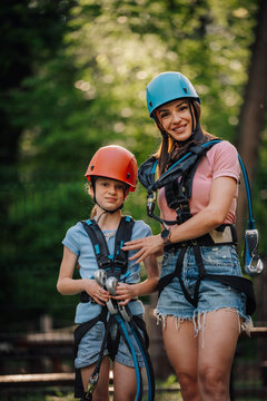Mother and daughter enjoying adventure park climbing with harness