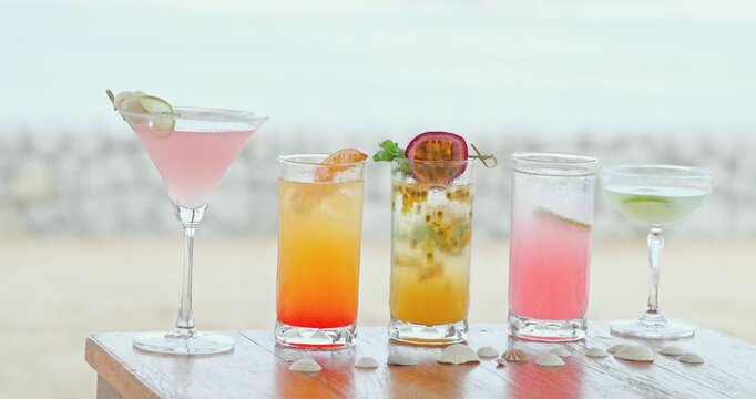 Tropical cocktails standing on wooden table, beach background with seashells, summer holiday vacation bar promotion