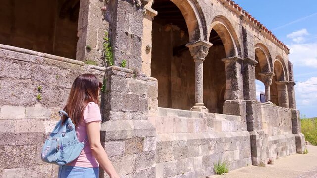 Young woman walking by the Romanesque El Salvador Church in Sepulveda