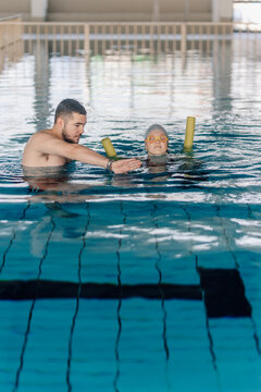Swimming instructor teaching adult woman lesson in pool