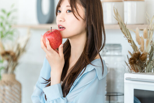 A woman eating an apple in the kitchen (diet, vegetarian)