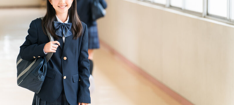 Elementary, middle, and high school girls in uniform walking down a school corridor.