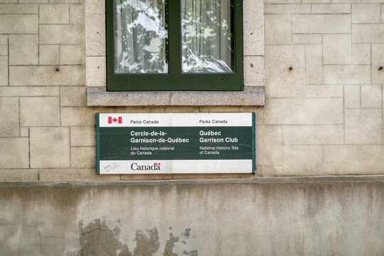 Quebec City, Quebec, Canada. July 26, 2026. Straight on view of Parks Canada Quebec Garrison Club sign on stone wall under window.